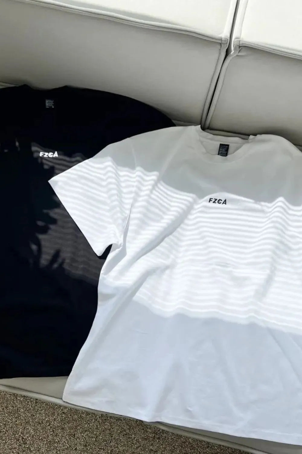 Oversized white and black t-shirts with drop shoulders and small chest logos.