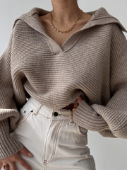 Tan knit sweater with wide collar and balloon sleeves, styled with white jeans.