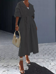 Black midi dress with lapel collar, tie waist, and cuffed sleeves.