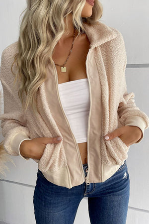 Cream teddy fleece bomber jacket with collared neck and zip front, styled with a white tube top and jeans.