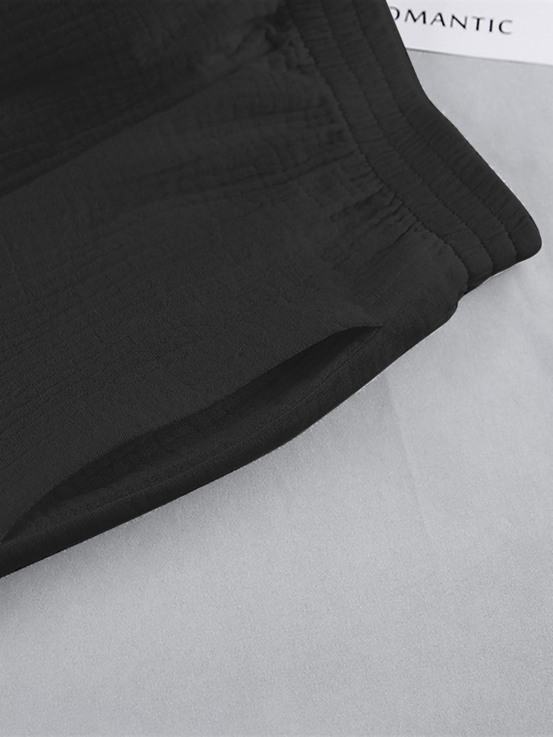 Black textured cotton lounge shorts with elastic waistband and side pocket detail.