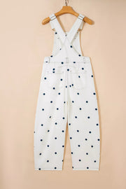 White denim overalls with navy polka dots, featuring buttoned straps and back pockets.