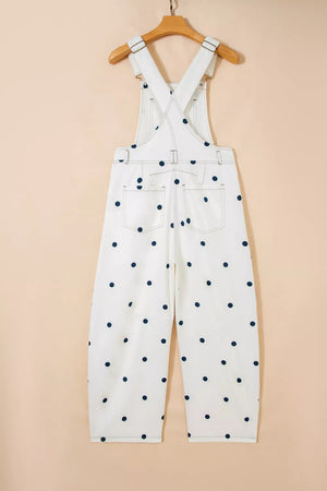 White denim overalls with navy polka dots, featuring buttoned straps and back pockets.