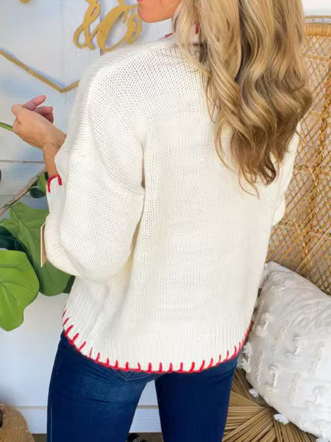 Ivory knit sweater with contrast red stitching on hem and cuffs.