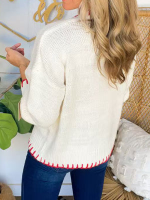 Ivory knit sweater with contrast red stitching on hem and cuffs.