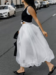 White midi skirt with sheer overlay and ruffled hem, worn with a black top.