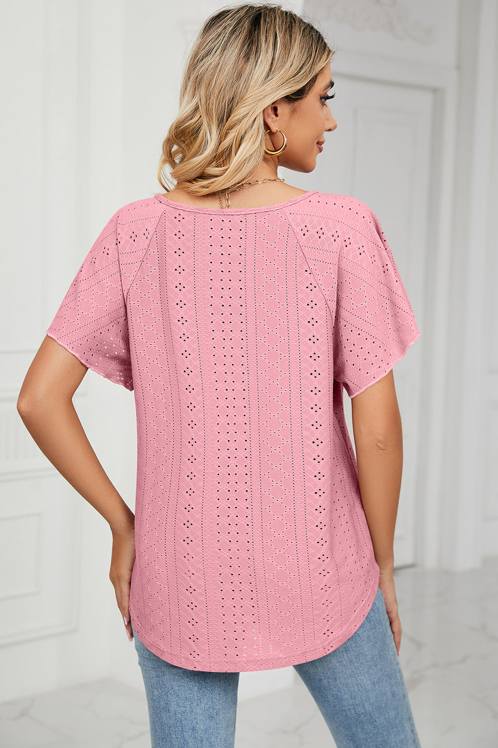 Pink eyelet blouse with flutter sleeves and a tie-neck detail.