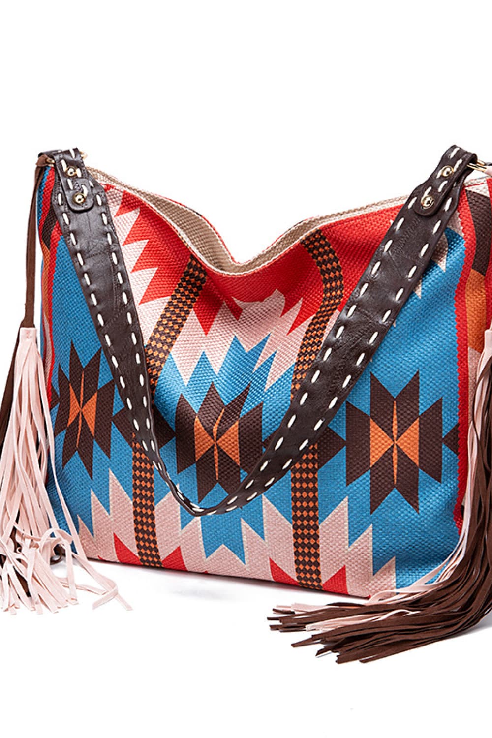 Southwestern fringe hobo bag with geometric pattern in multicolor canvas and brown leather trim.