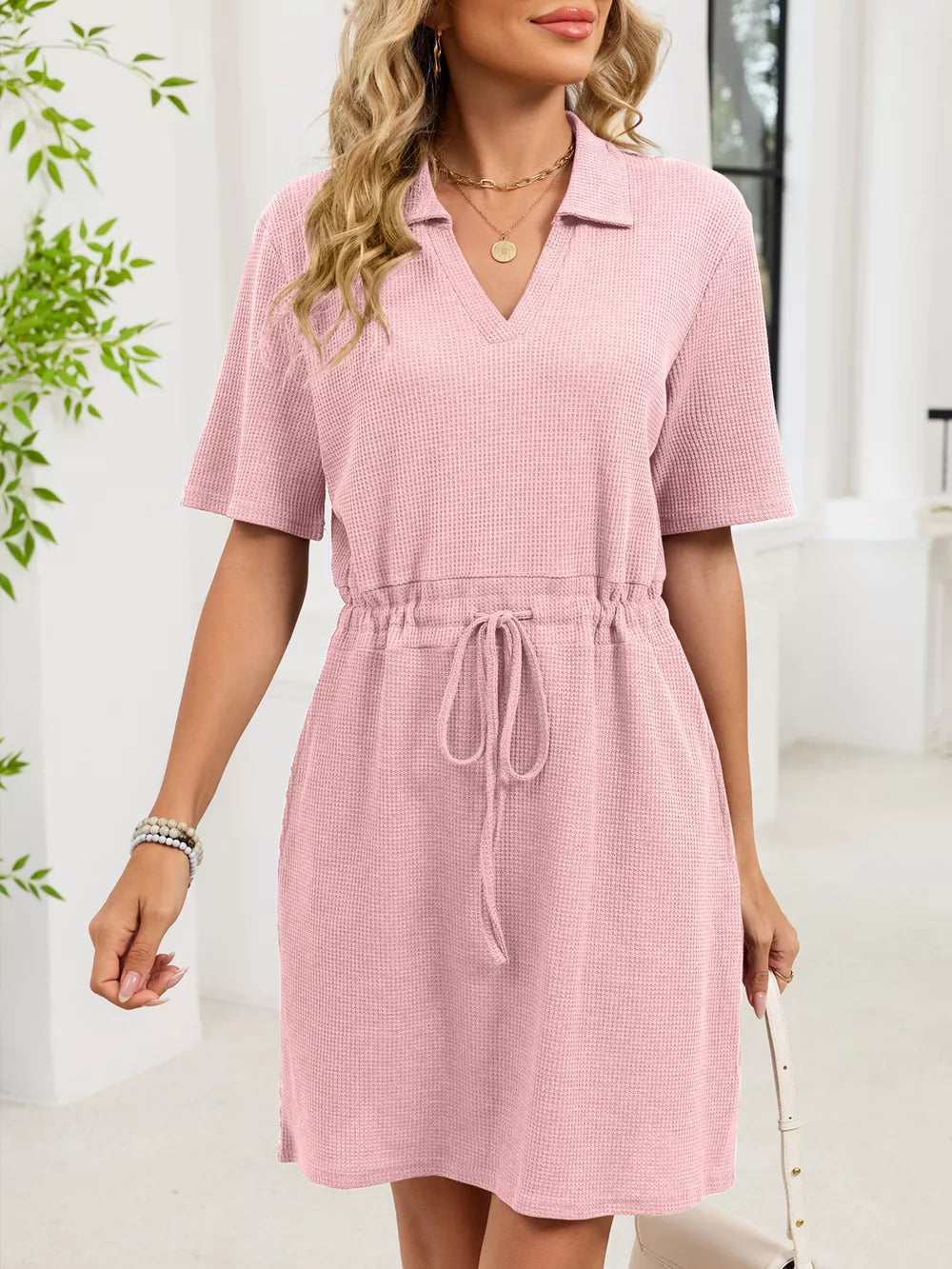 Pink textured polo dress with short sleeves and adjustable drawstring waist.