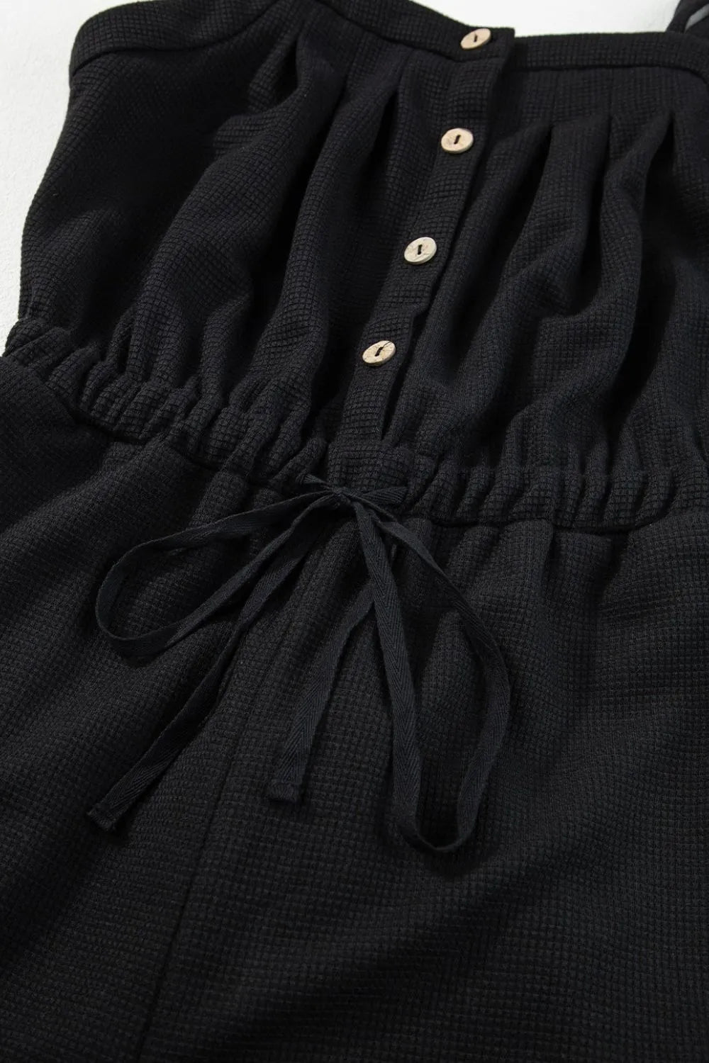 Black waffle knit jumpsuit with drawstring waist and button front detail
