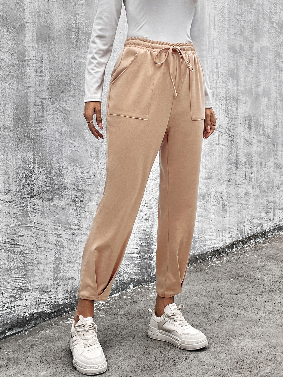 Beige tapered hemline utility joggers with drawstring waist and pockets.