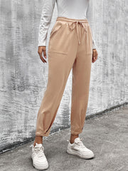 Beige tapered hemline utility joggers with drawstring waist and pockets.