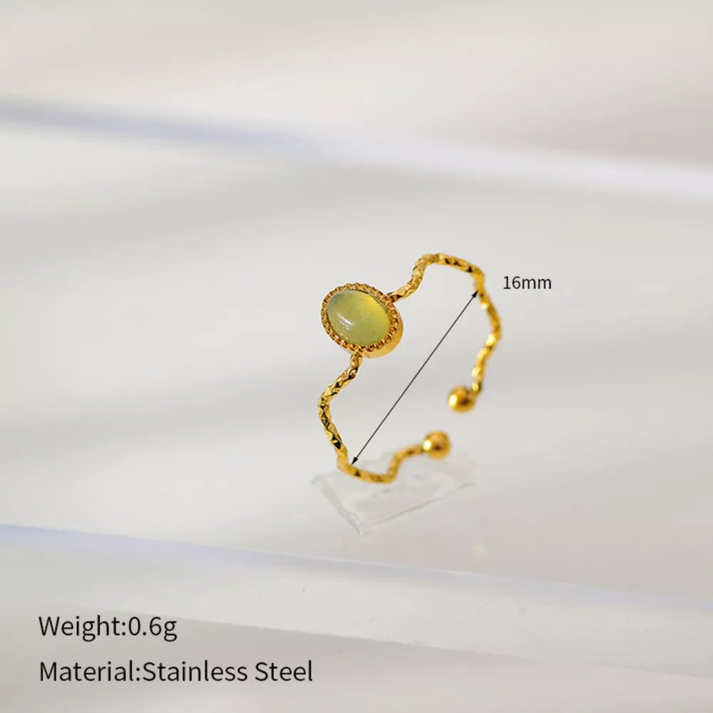 Wavy gold-plated ring with oval cream natural stone and textured band.