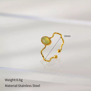 Wavy gold-plated ring with oval cream natural stone and textured band.