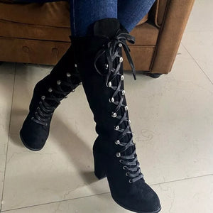 Black suede lace-up block heel boots with silver eyelets and ties.