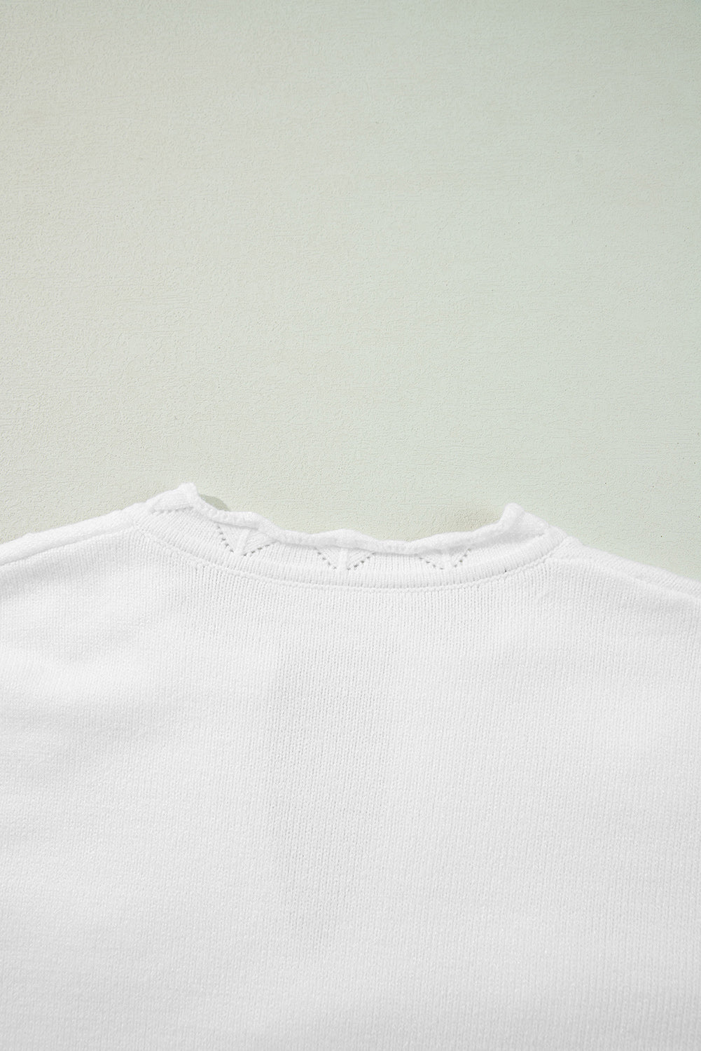 White knit sweater with scalloped notch neck detail and subtle eyelet pattern.