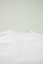 White knit sweater with scalloped notch neck detail and subtle eyelet pattern.