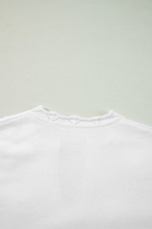 White knit sweater with scalloped notch neck detail and subtle eyelet pattern.