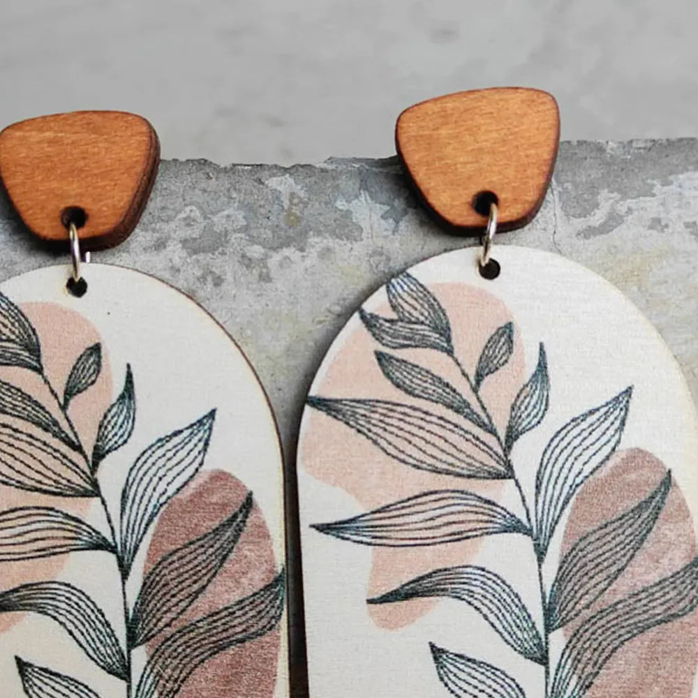 Botanical arch wood earrings with dusty pink and apricot abstract shapes and line art leaves.