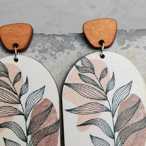 Botanical arch wood earrings with dusty pink and apricot abstract shapes and line art leaves.