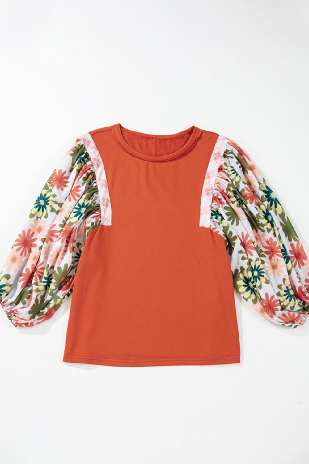 Orange-red blouse with floral patchwork balloon sleeves and a round neckline.