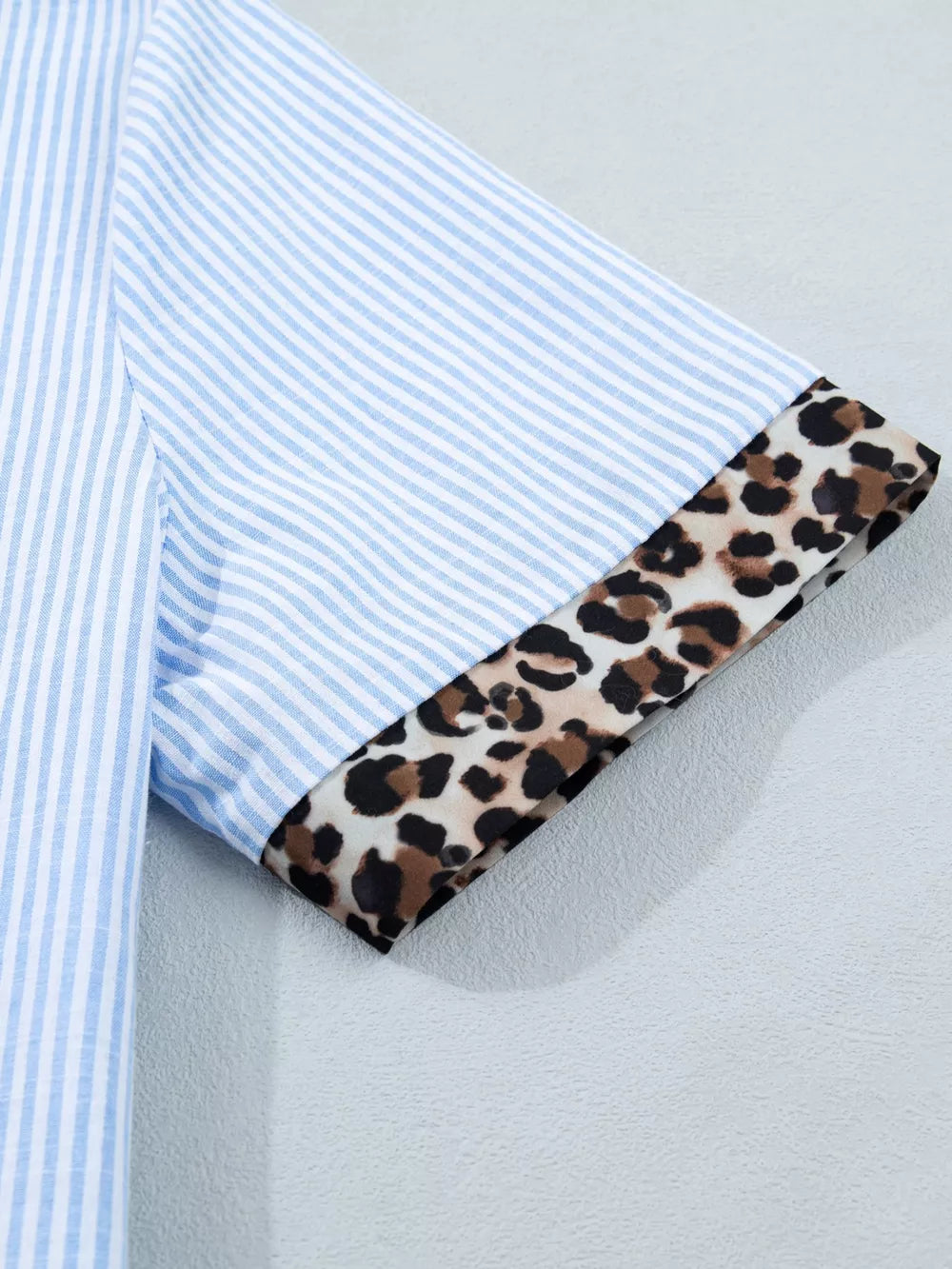 Blue striped button-down shirt with leopard print cuffs