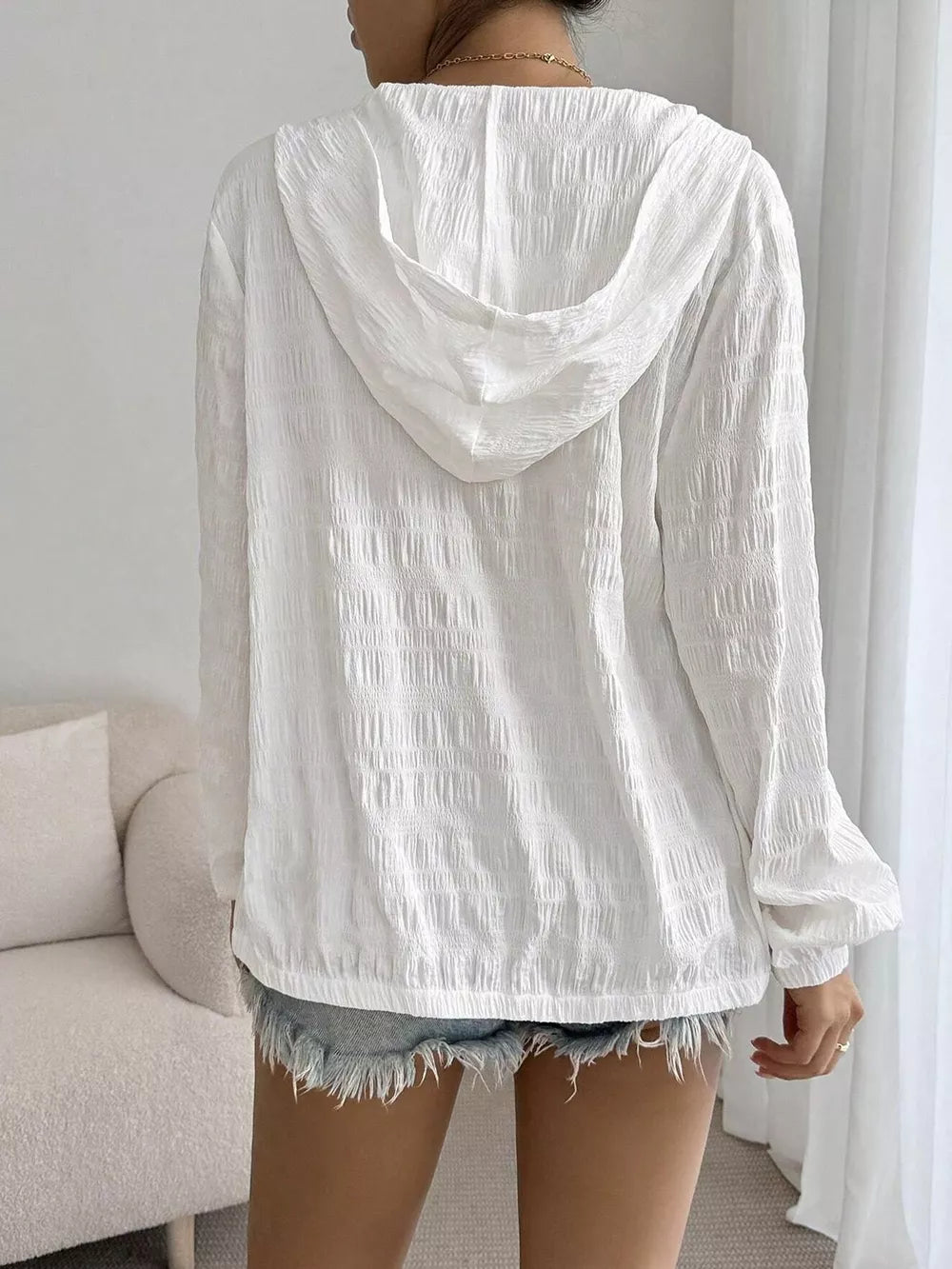 White crinkled hooded jacket with long sleeves and elastic cuffs.