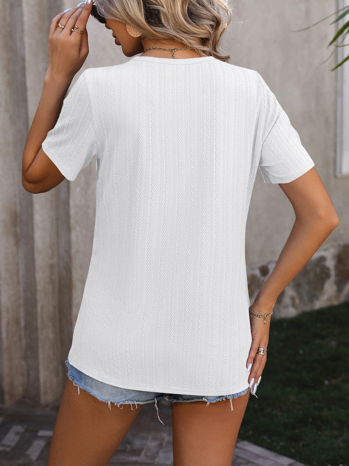 White textured t-shirt with short sleeves and split hem, styled with denim shorts.