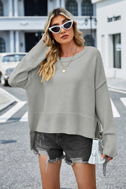 Gray acrylic knit sweater with flared sleeves and slit hem detail.