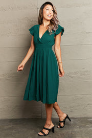 Emerald green pleated flutter sleeve dress with V-neck and cinched waist