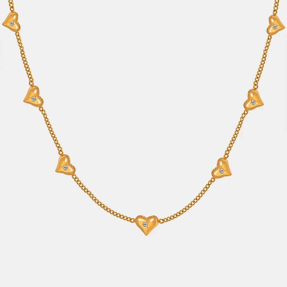 Gold chain necklace with scattered heart charms, each with a small zirconia stone.