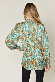 High neck abstract print blouse in green with smocked cuffs and puffed shoulders.