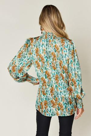 High neck abstract print blouse in green with smocked cuffs and puffed shoulders.
