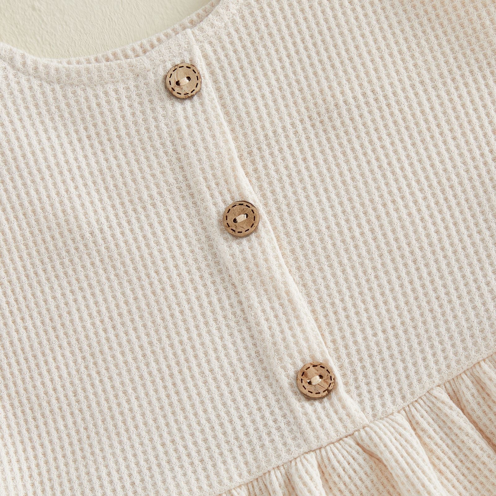 Apricot waffle knit tank top with wooden buttons and ruffled hem detail.