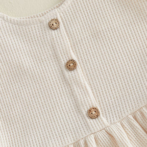 Apricot waffle knit tank top with wooden buttons and ruffled hem detail.