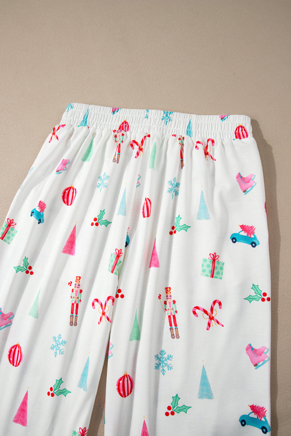 White pajama pants with festive Christmas print including nutcrackers, candy canes, trees, and gifts.