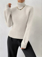 White ribbed turtleneck sweater with long sleeves and a gold chain necklace.