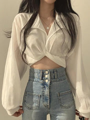 White polyester long sleeve shirt with knot front detail, buttoned collar, and cropped length.