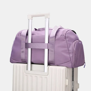 Sportsnew Nylon Duffle in Mauve with mesh pocket and adjustable strap, resting on a suitcase.