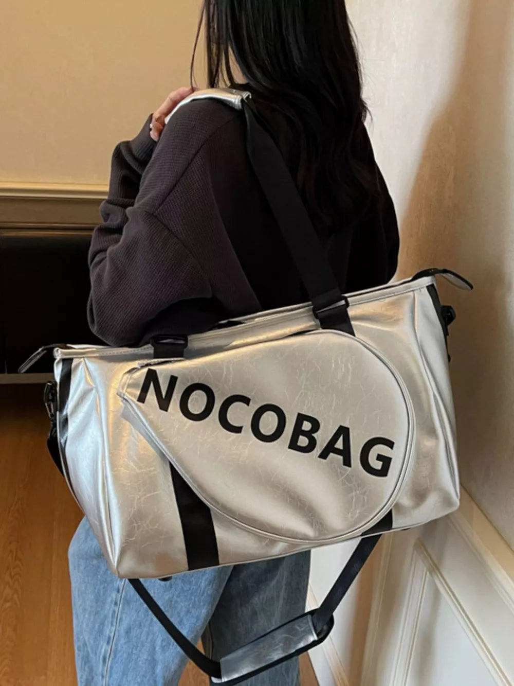 Silver leather duffel bag with black straps and "NOCOBAG" text detail.