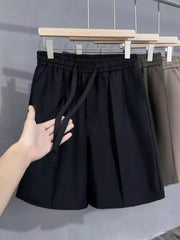 Black pleated chino shorts with drawstring waist and pockets, cotton blend.