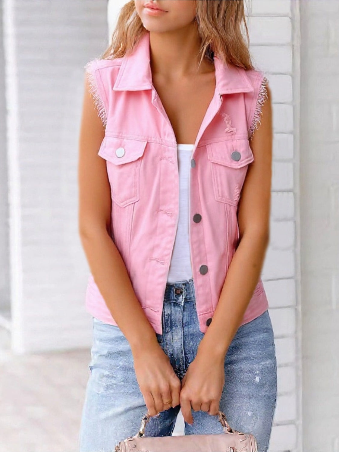 Pink denim vest with frayed shoulders and distressed details.