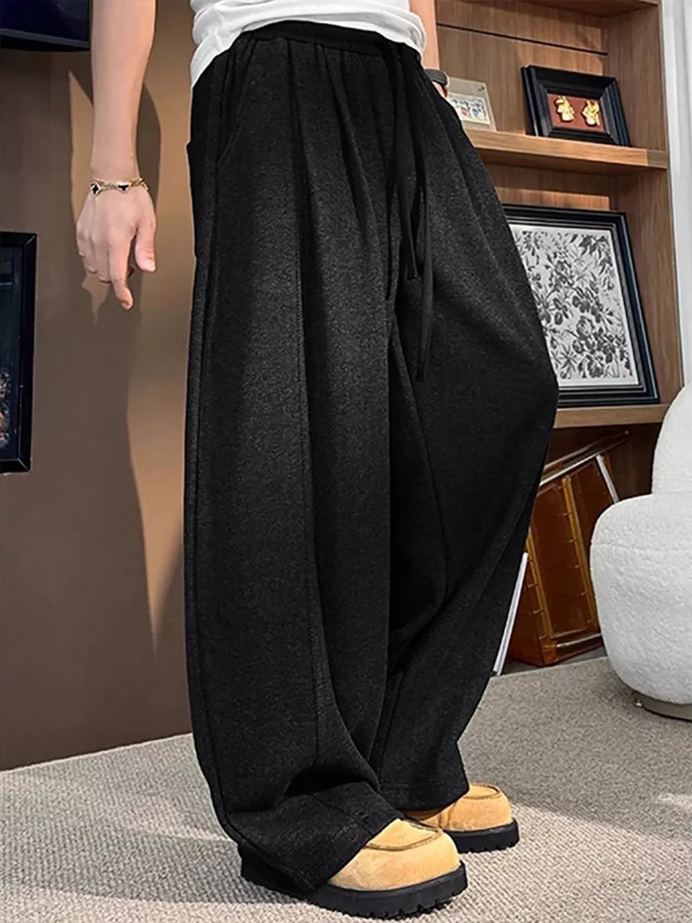 Black sweatpants with a loose fit and drawstring, shown on a man.