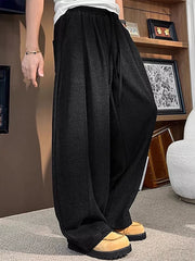 Black sweatpants with a loose fit and drawstring, shown on a man.