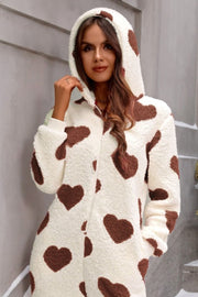 Cream sherpa onesie with brown hearts, hood, and long sleeves.