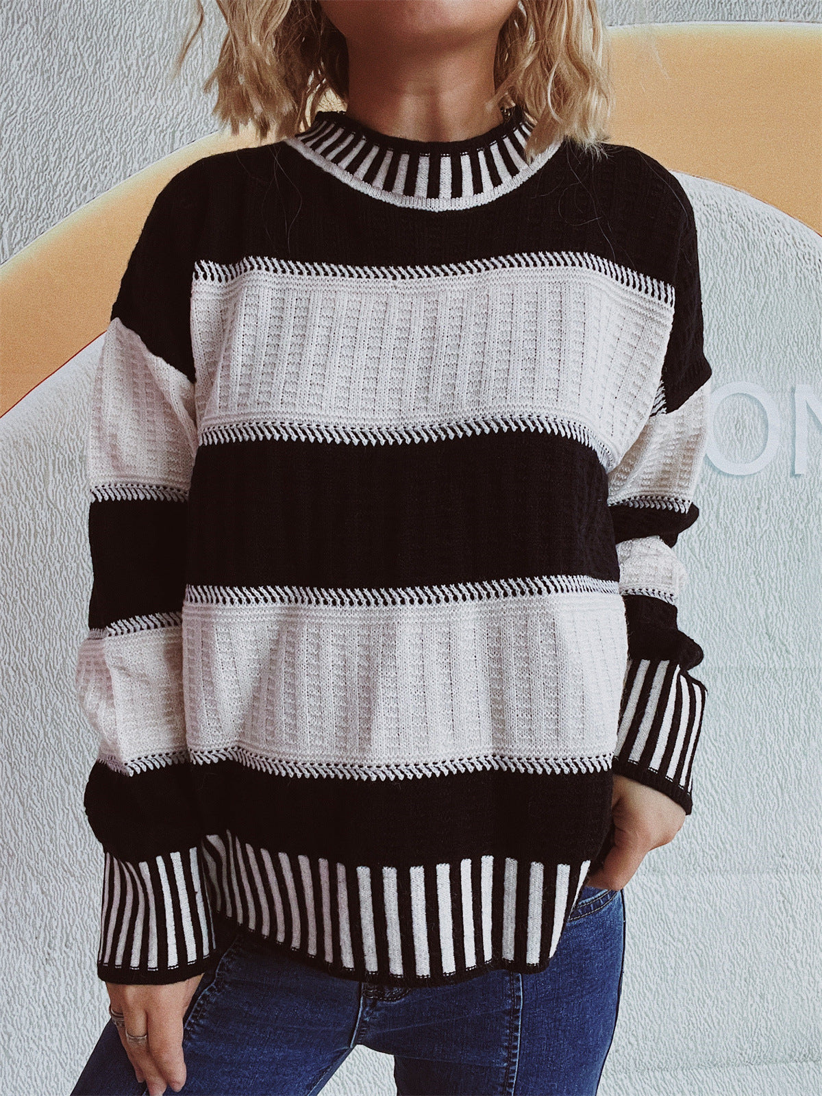 Black and white striped mock neck knit sweater with textured panels.
