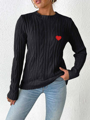 Black cable knit sweater with embroidered red heart detail.