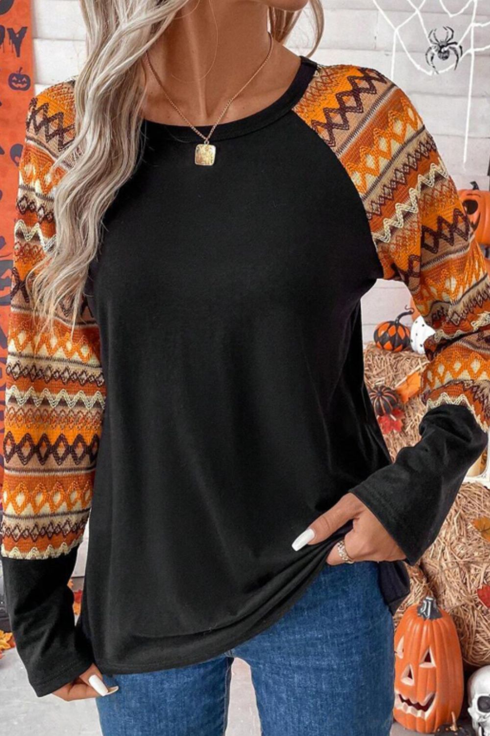 Black raglan tee with Aztec print sleeves in tangerine and brown, crew neck, long sleeves.