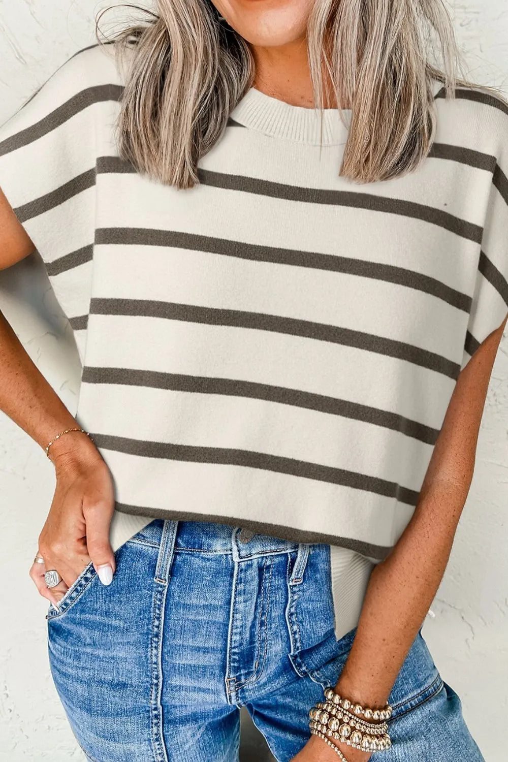 Striped knit cap-sleeve top with a crew neck and slit hem, styled with jeans.