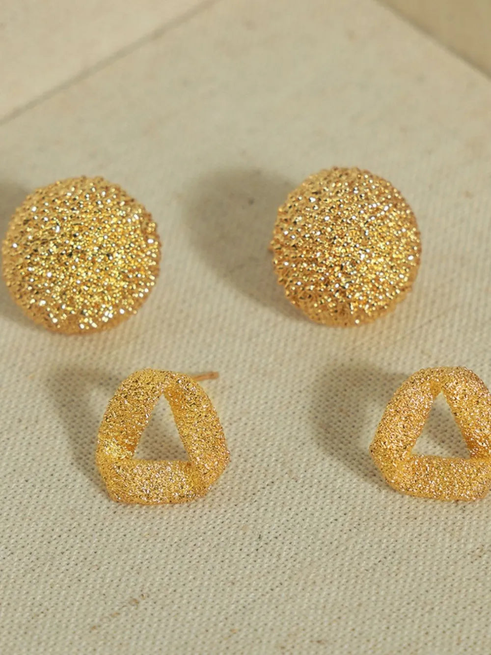Textured gold cube earrings, round and triangular styles, with a sparkling finish.